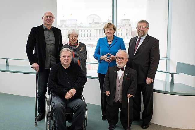 Gruppenfoto: Detlef Eckert, ABiD e.V., Ilja Seifert, ABiD e.V., Ulrike Mascher, Sozialverband VdK Deutschland e.V., Bundeskanzlerin Angela Merkel, Volker Langguth-Wasem, BAG-Selbsthilfe e.V.,  Adolf Bauer, SoVD e.V.